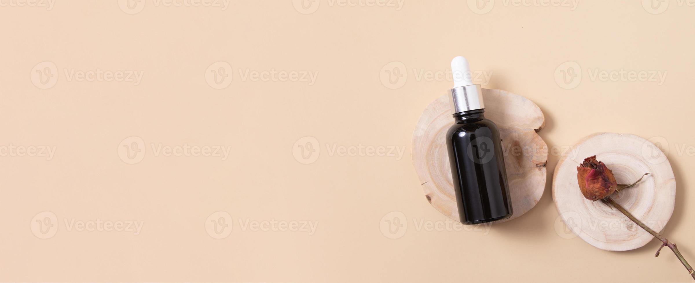 banner met houten podium of voetstuk met druppelflesje cosmetische olie of serum bovenaanzicht. neutraal beige monochroom huidverzorgingsconcept. plat leggen foto