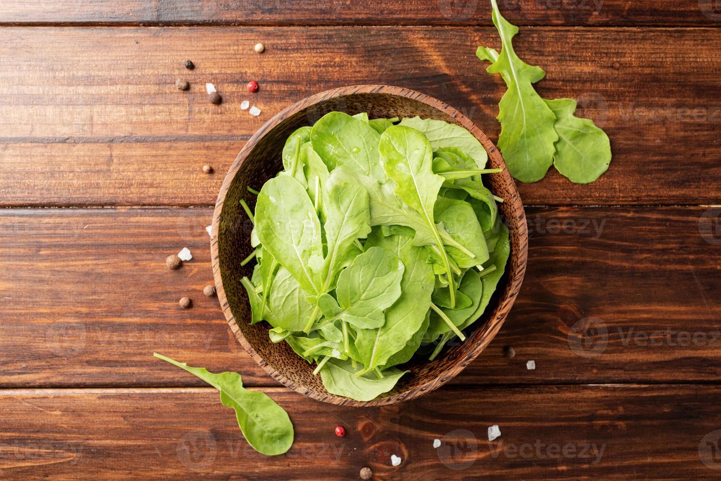 verse rucola bladeren in bruine kom bovenaanzicht foto