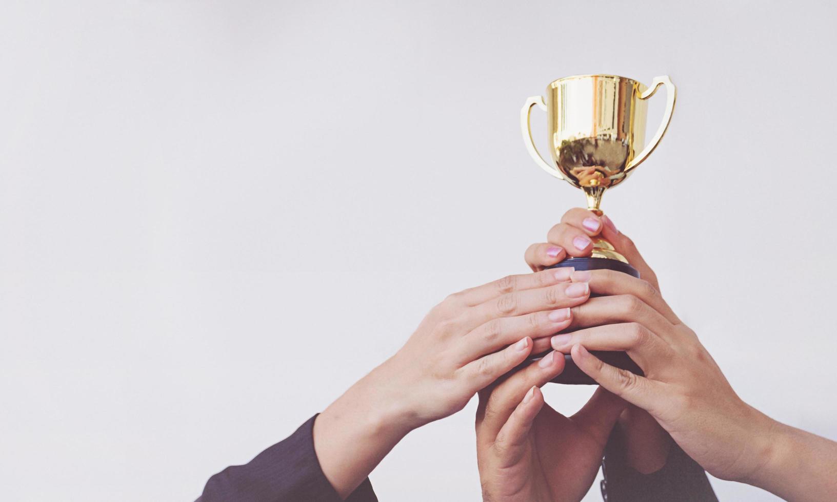 hand van teamzaken met een gouden trofee, concept teamwork foto