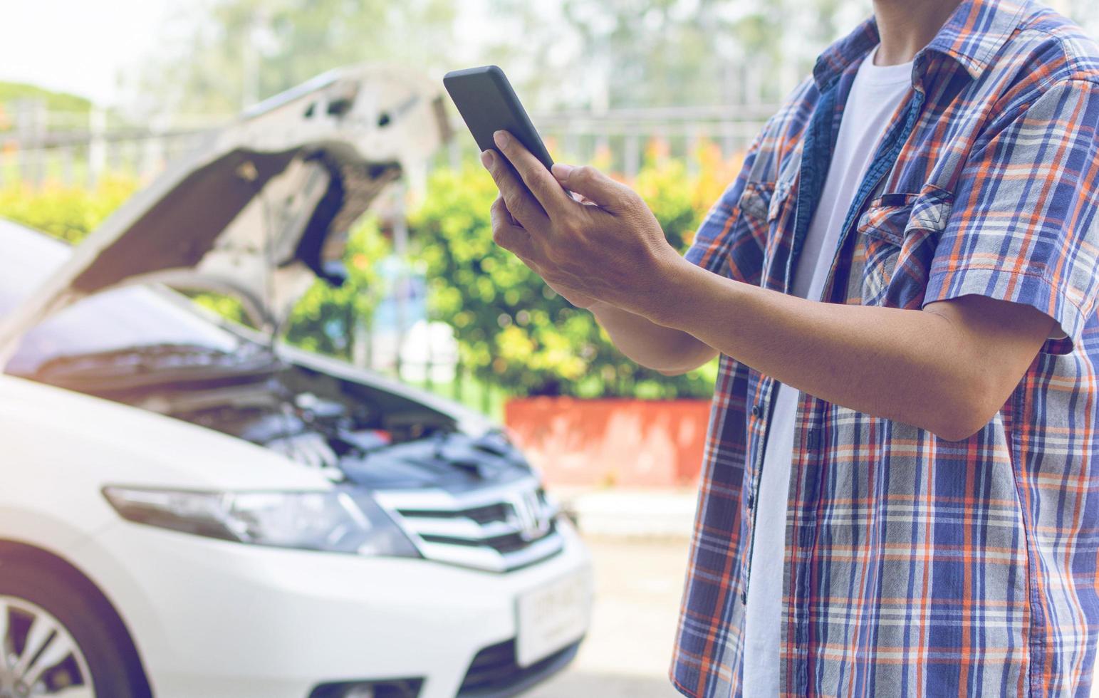 Azië man staat voor een kapotte auto die om hulp roept foto