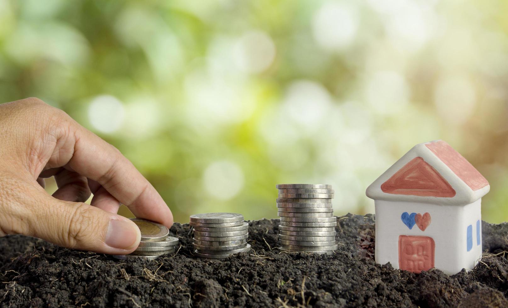 geld besparen om een huisconcept, huis en munten in aarde te bouwen foto