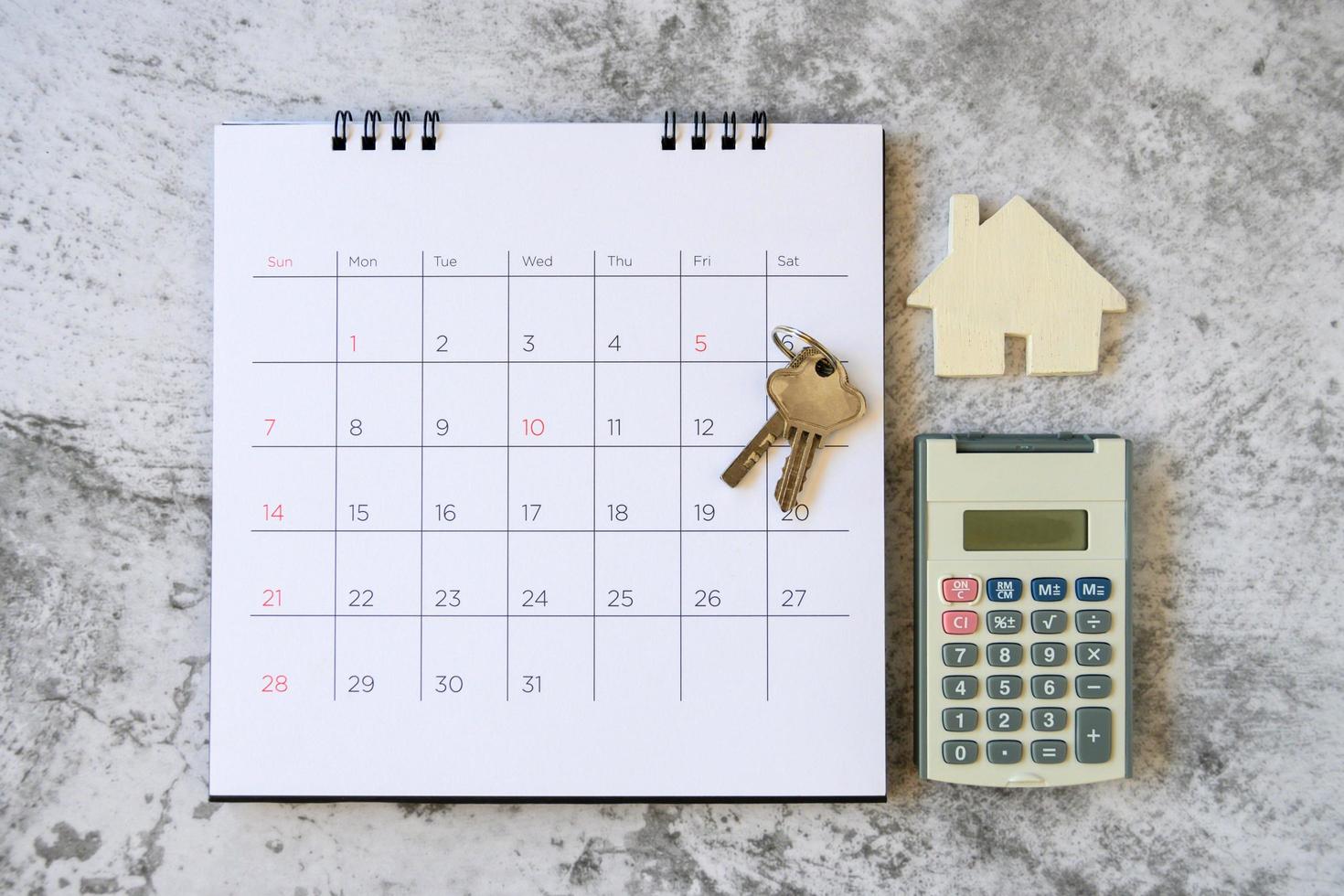 kalender en huis op tafel. dag van aan- of verkoop van een huis of betaling voor huur of lening. foto