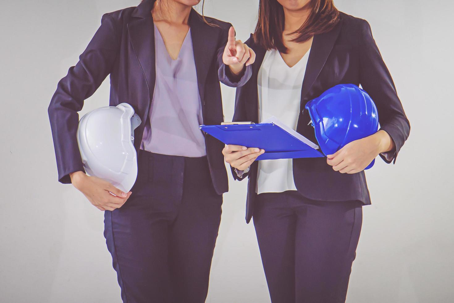twee bedrijfsvrouwen industrieel ingenieurs helmen met een tablet in handen foto