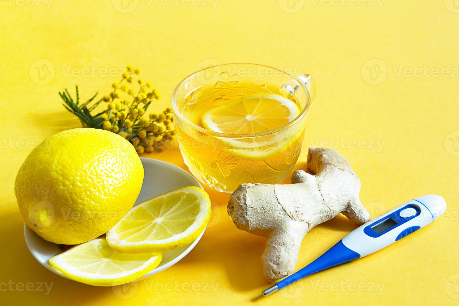 geneeskrachtige thee in een kopje, gember, citroen, acacia-versterk het immuunsysteem in het koude seizoen, thermometer - vlak. vitaminedrank voor gezondheid en ingrediënten op gele achtergrond. foto