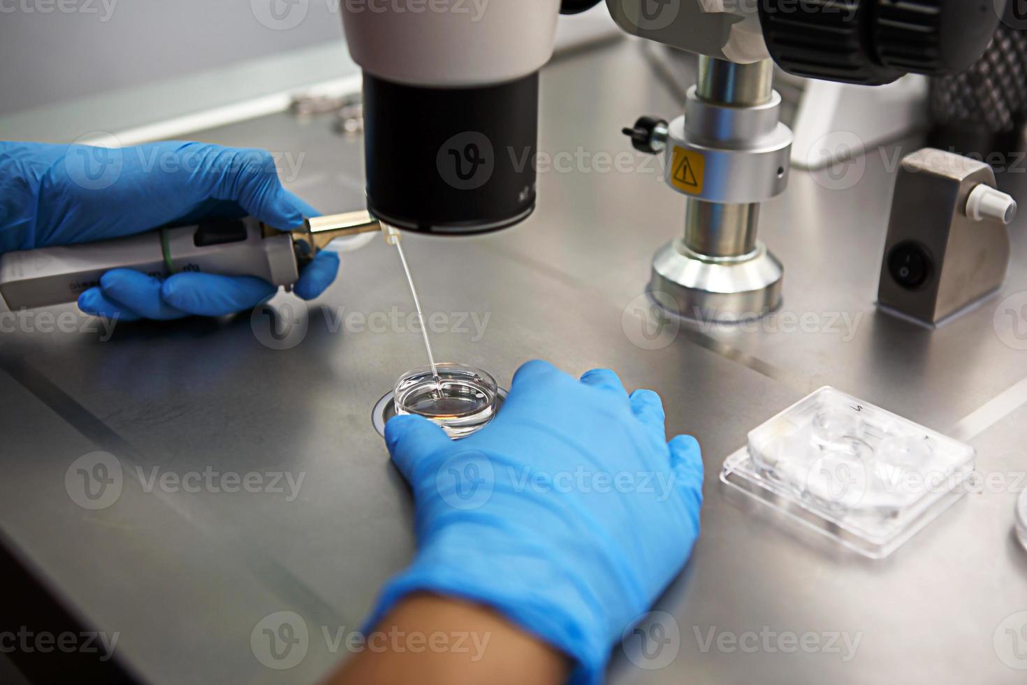 handen van een wetenschapper in het laboratorium met een reageerbuis en een microscoop. de uitvinding van het vaccin, een arts in de kliniek van kunstmatige inseminatie ivf. tests, bevruchting van het ei foto