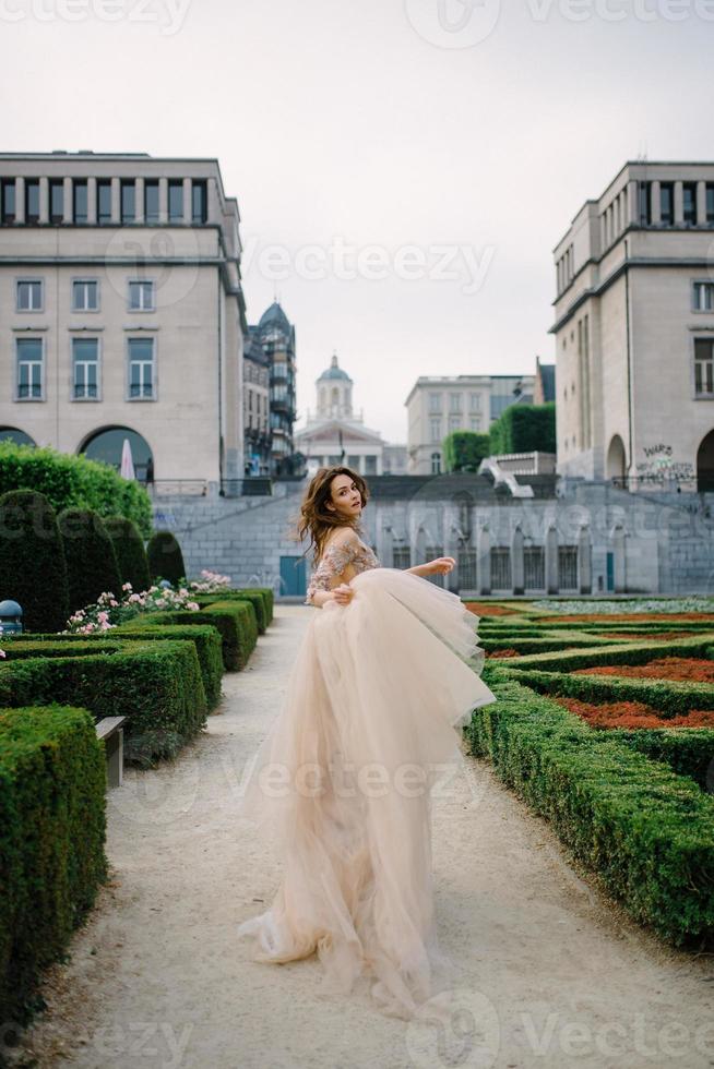 portret van een lieftallig jong meisje in een weelderige jurk die door het park en het grote paleis loopt foto