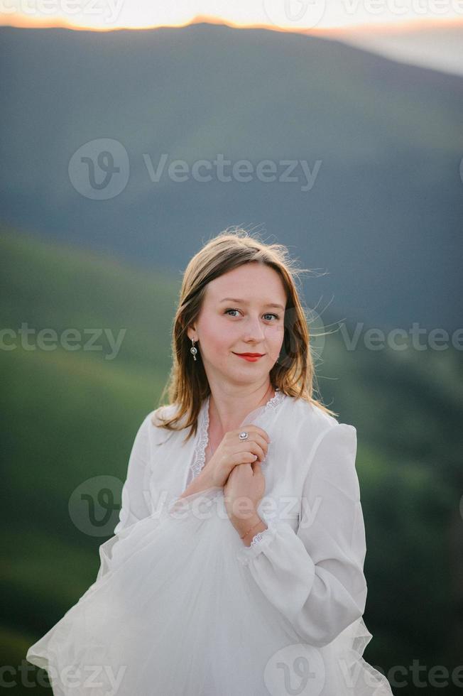 vrouw in trouwjurk rent over het veld naar de bergen foto