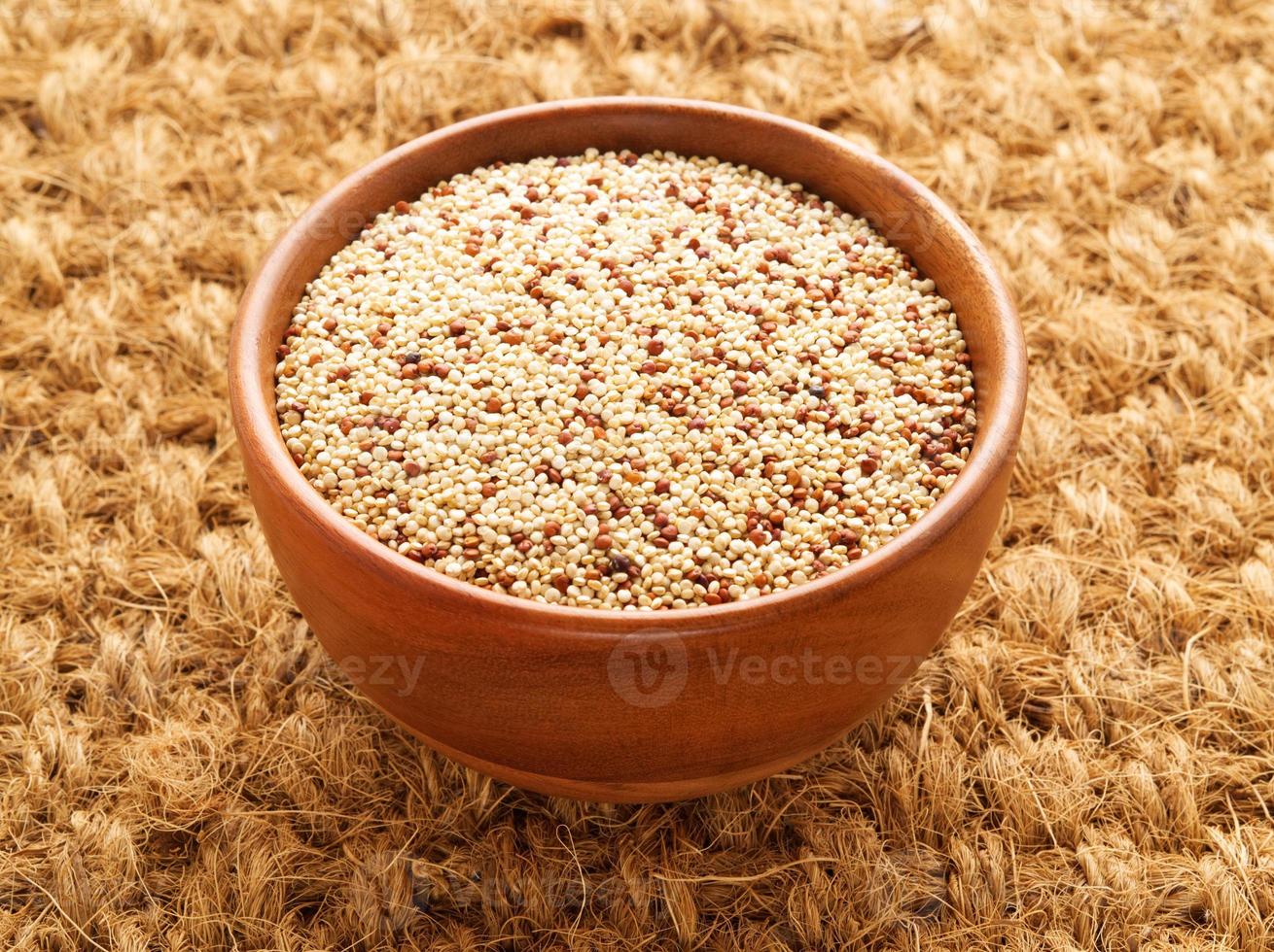 rauwe quinoa in houten kom, superfood. bruine sisal mat achtergrond, zijaanzicht. foto