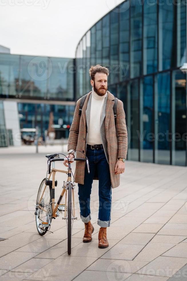 jonge bedrijfsleider die op de fiets gaat werken. milieuvriendelijk vervoer. verticale afbeelding foto