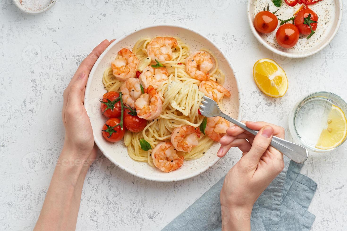 pasta bavette met gebakken garnalen, bechamelsaus. vrouw handen in frame, meisje eet pasta, bovenaanzicht foto