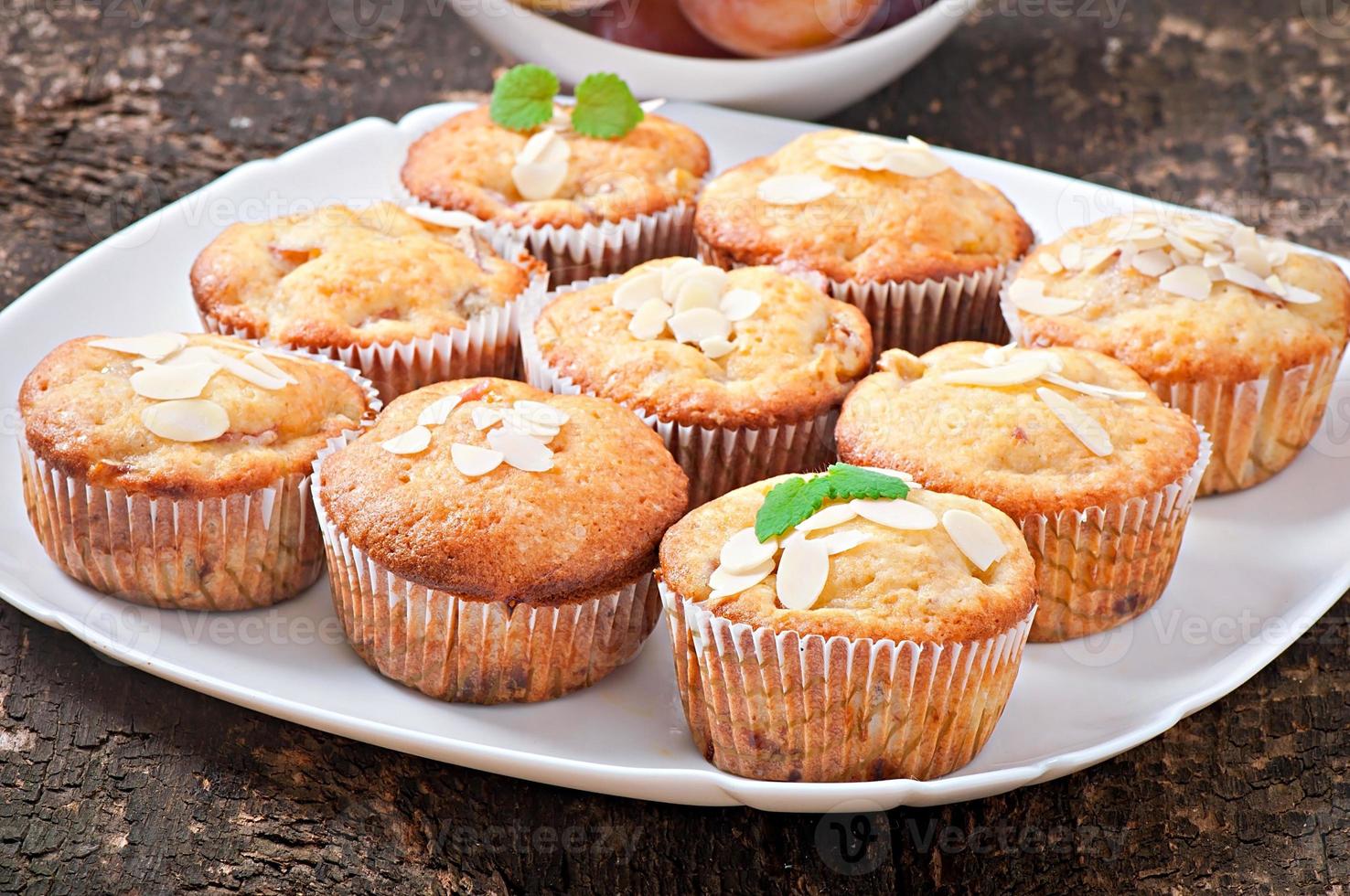 muffins met pruimen en amandelblaadjes versierd met muntblaadjes foto