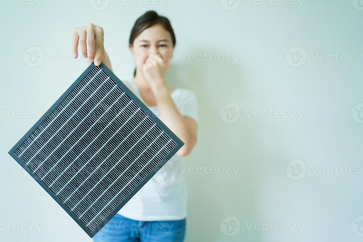 aziatische jonge vrouw die een gebruikte en de nieuwe luchtzuiveringsfilter toont, waarbij de gebruikte vuile en nieuwe luchtfilter wordt vergeleken. foto