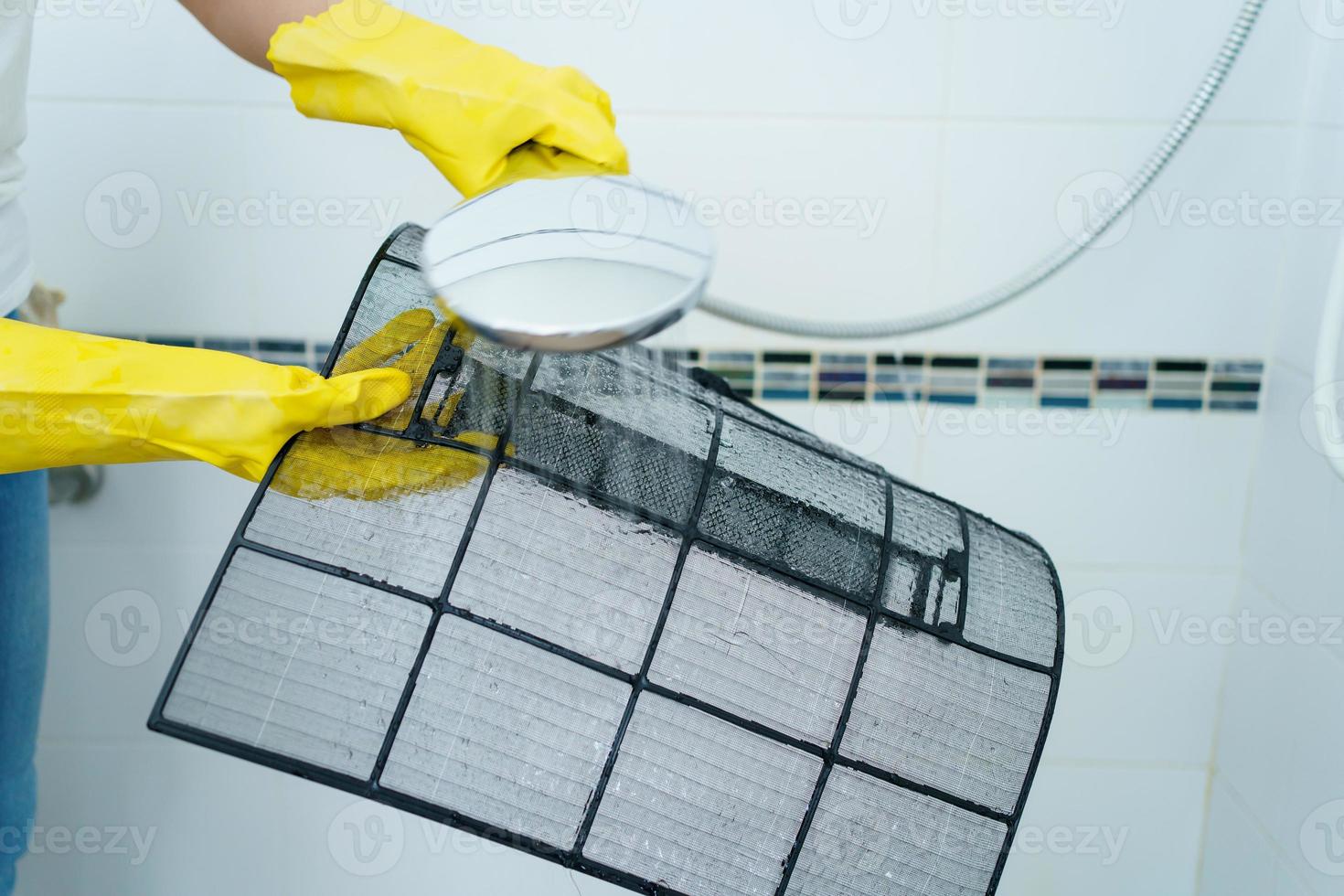 aziatische vrouw die een vuil en stoffig airconditioningfilter in haar huis schoonmaakt. huisvrouw die een stoffig airconditionerfilter verwijdert. foto