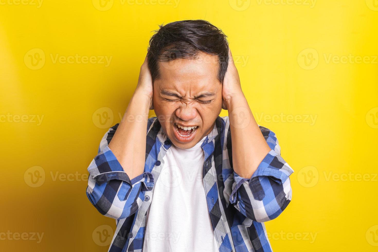 close-up portret van Aziatische man met uitdrukking van stress, wanhoop, frustratie geïsoleerd op gele achtergrond foto