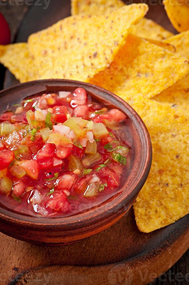 Mexicaanse nacho chips en salsa duik in kom op houten achtergrond foto