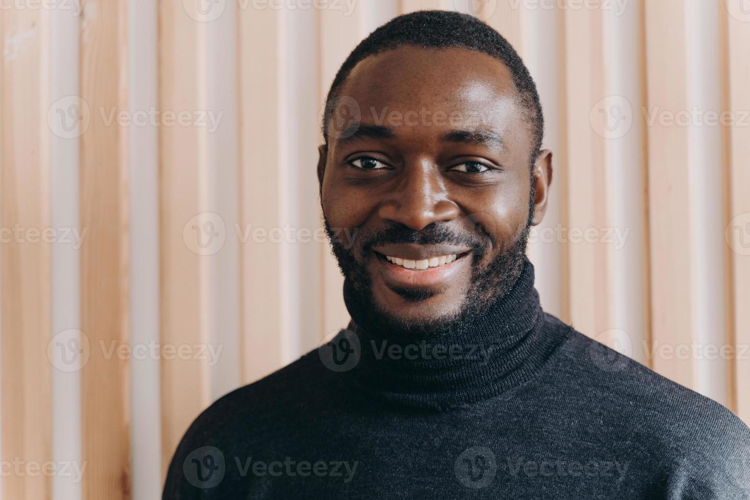 portret van een vrolijke, vrolijke Afro-Amerikaanse man die lacht naar de camera en positieve emoties uitdrukt? foto