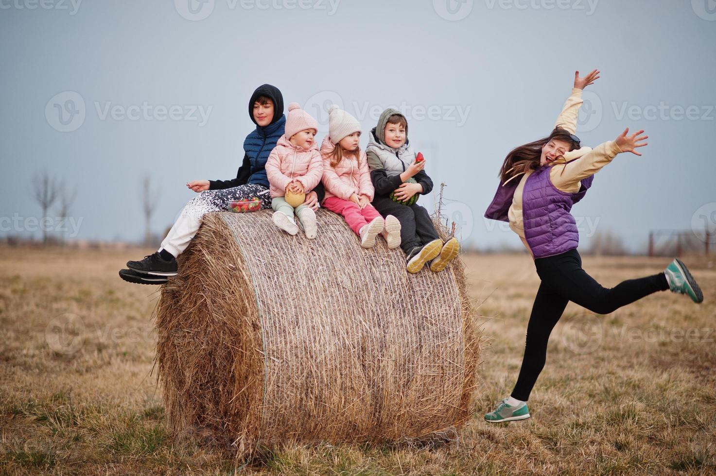 vier kinderen met moeder plezier op haycock op veld. foto