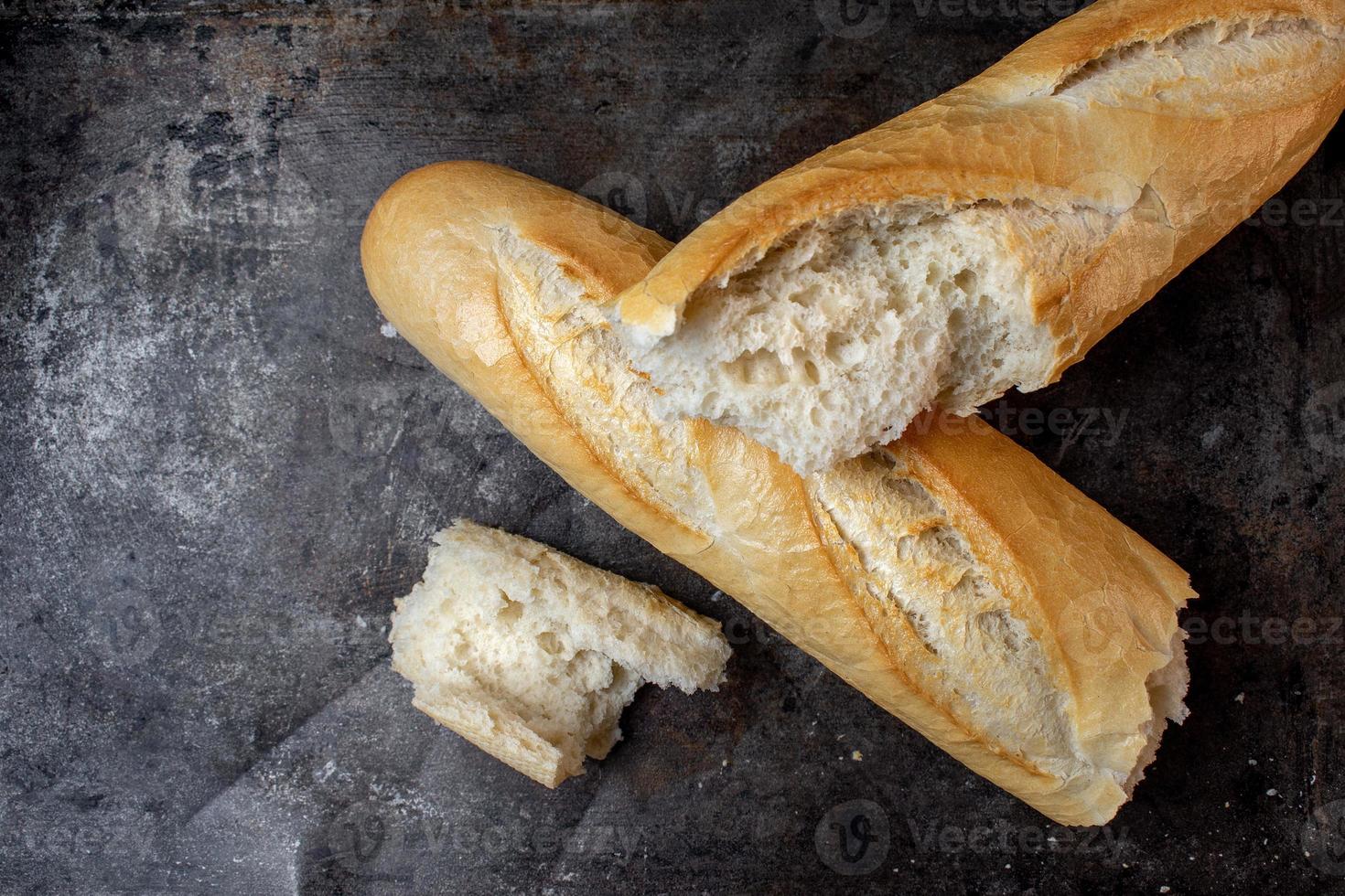 geïsoleerd stokbrood in verschillende stukken op donkere metalen achtergrond plat leggen foto