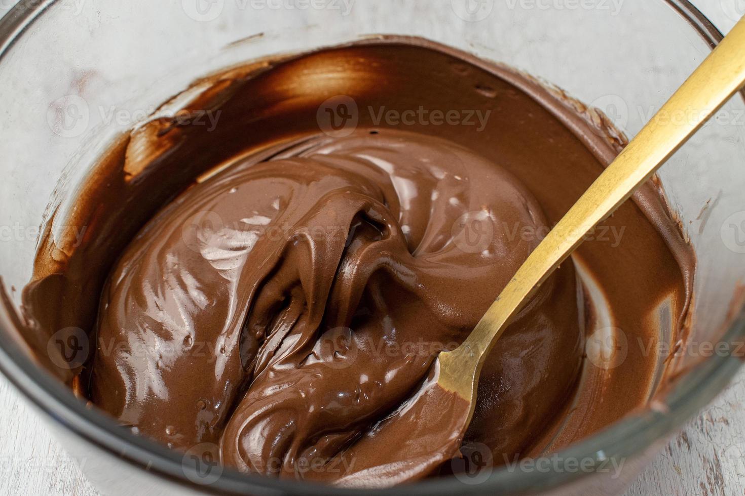 glazen kom gesmolten chocolade met lepel foto