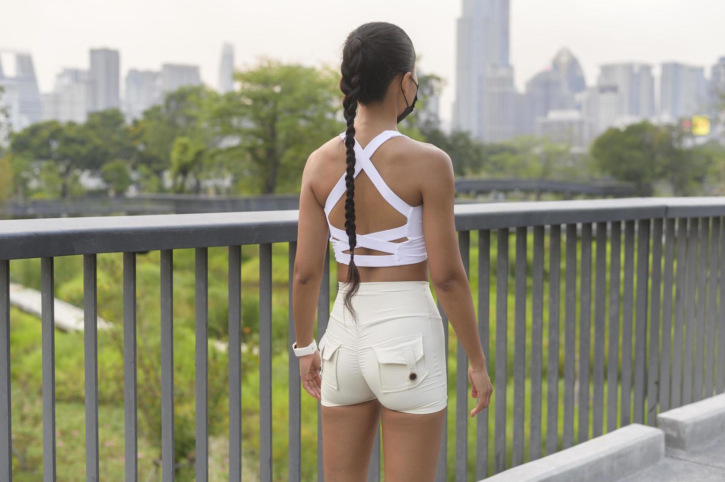 jonge fitnessvrouw in sportkleding die een gezichtsmasker inneemt tijdens het sporten in het stadspark, gezondheid en levensstijl. foto