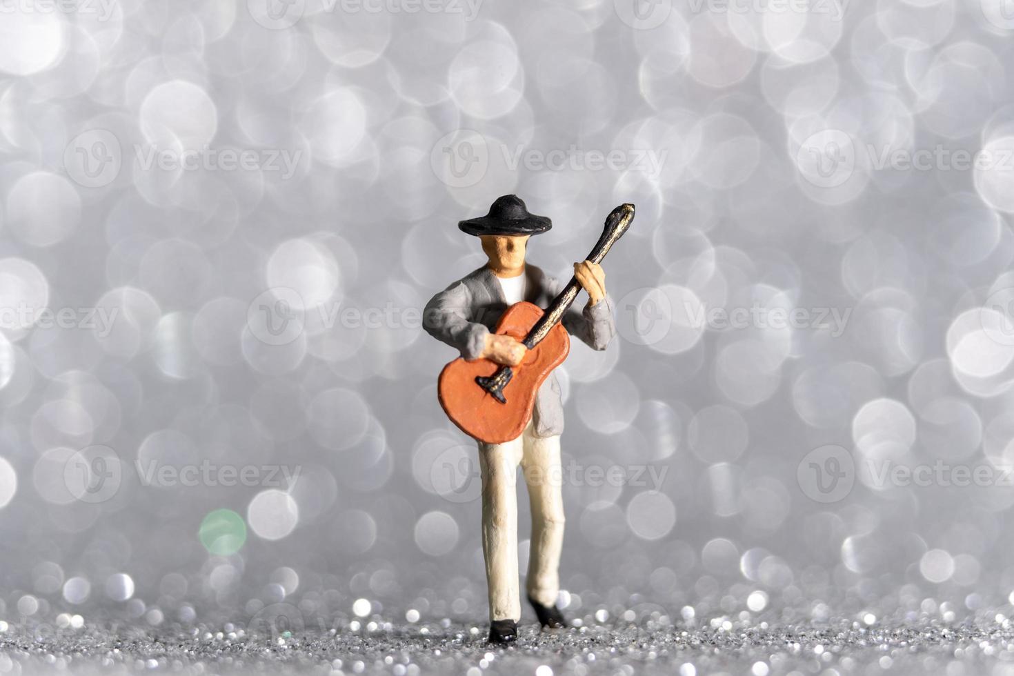 miniatuurmuzikant met gitaar op bokehachtergrond foto