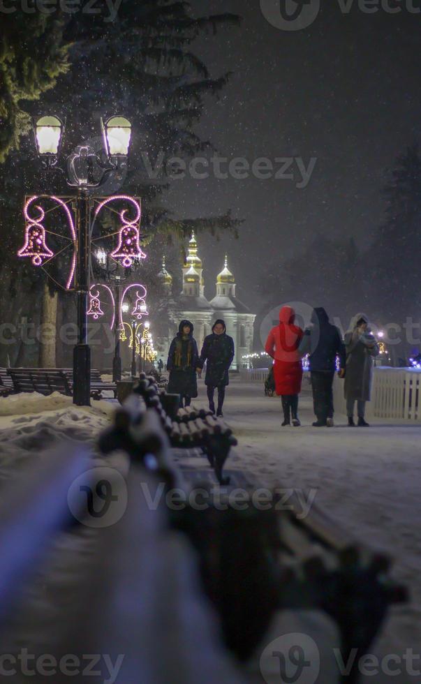 close-up foto van een straatlantaarn in het donker in de winter met vallende sneeuwvlokken. straat ingericht voor kerstmis en nieuwjaar. avond magische sfeer. straat 's nachts. straat retro verlichting.