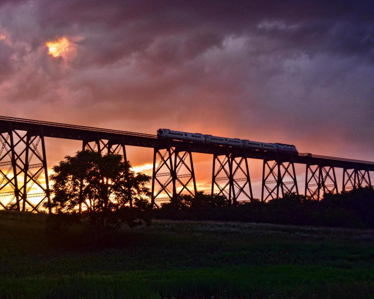 trein gaat over een brug bij zonsondergang foto