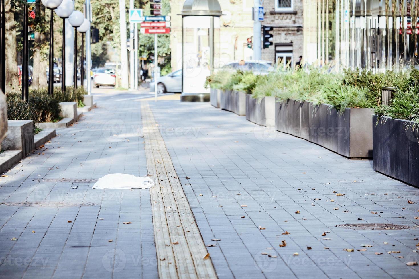 betegelde stoep met droge gevallen herfstbladeren stedelijke straat met liggende witte plastic boodschappentas foto