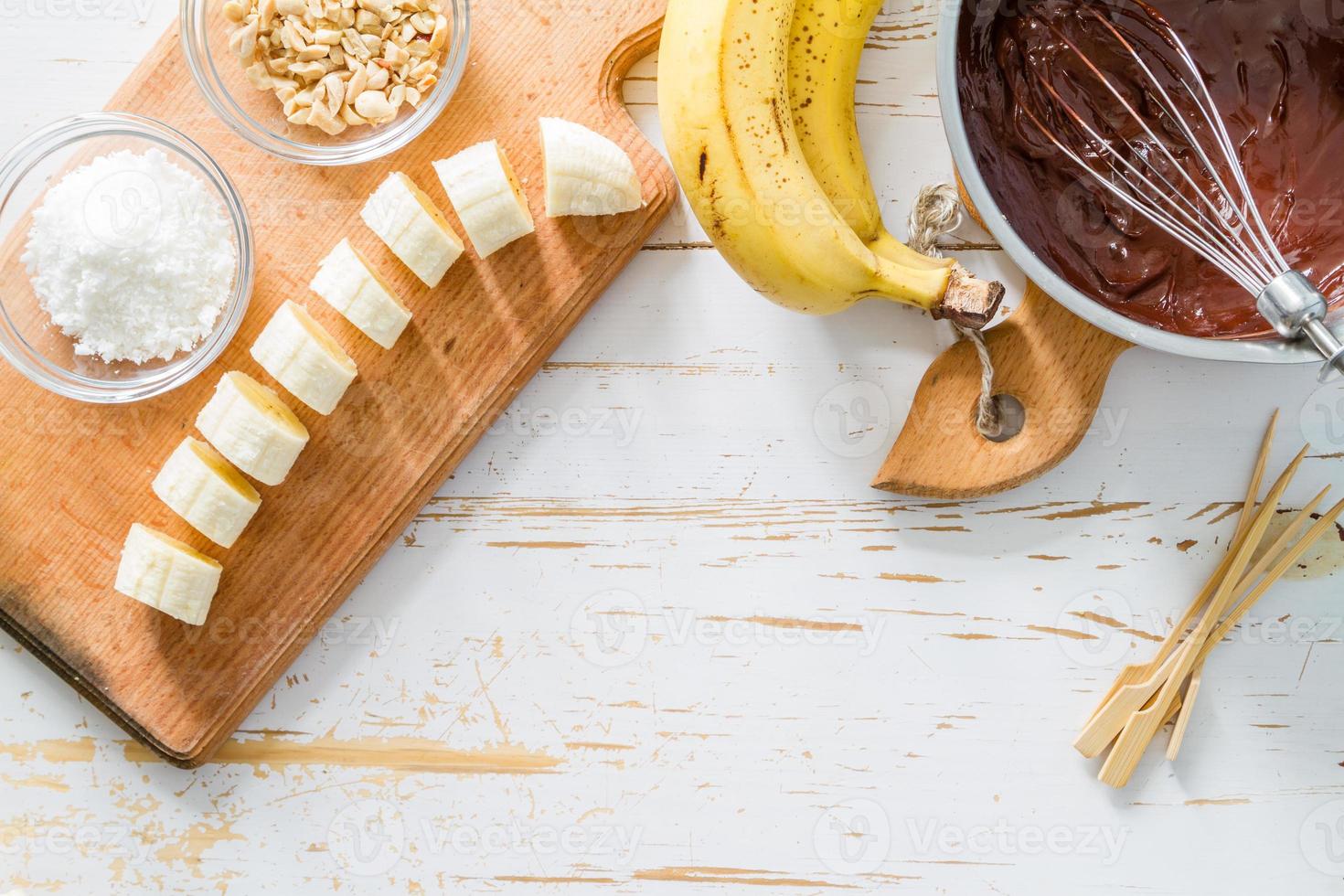 banaan pops voorbereiding - banaan, chocolade, noten, kokospoeder, stokken foto