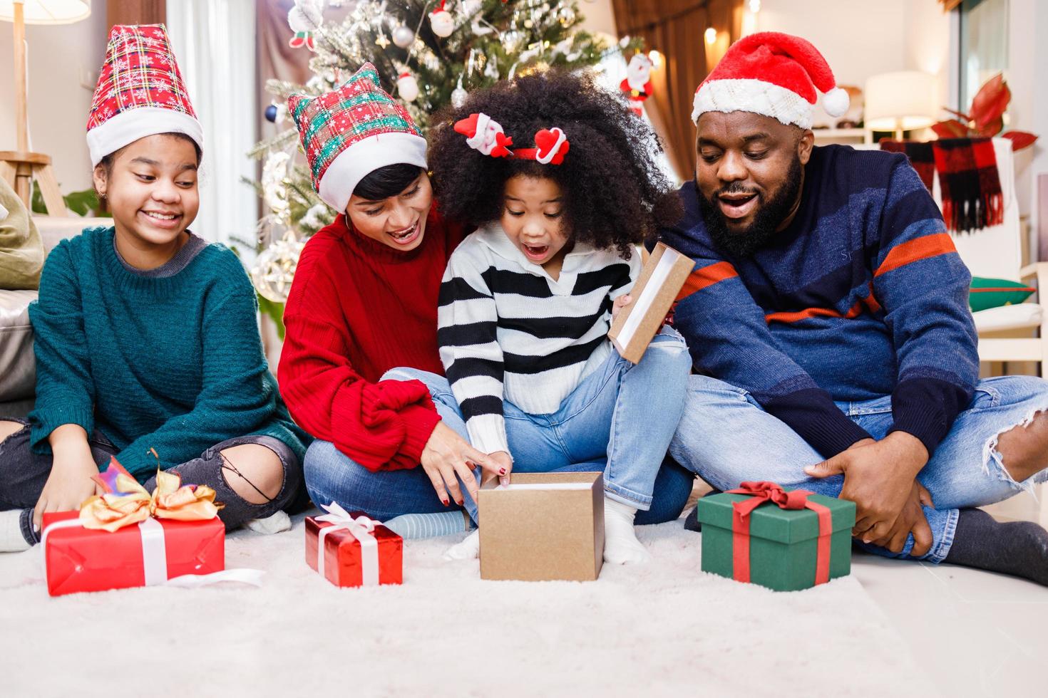 afro-amerikaanse familie verrast met een cadeau op eerste kerstdag. Vrolijk Kerstfeest foto