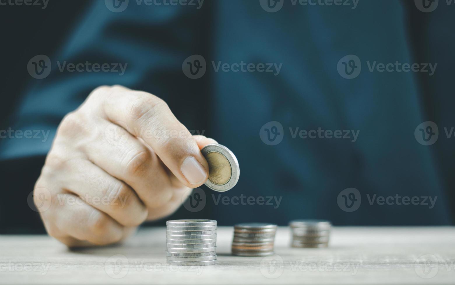 met de hand munten op stapel munten, spaargeld en inkomsten of investeringen. foto