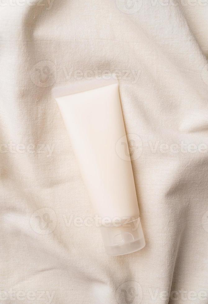 bovenaanzicht mockup gezichtsverzorgingsproduct witte buis met blanco label op farbic golvende achtergrond foto