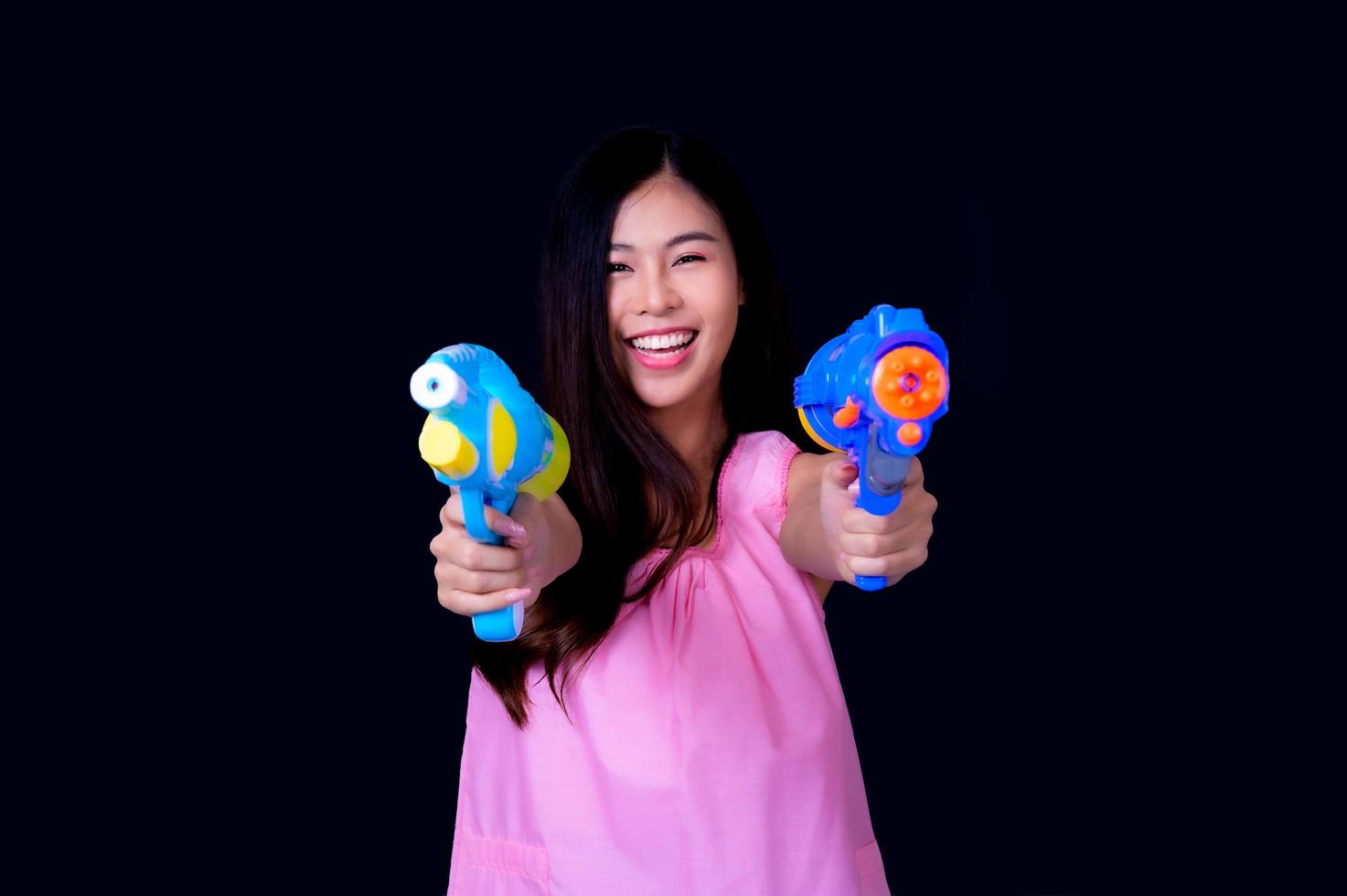 een mooie Aziatische vrouw toont een gebaar terwijl ze een plastic waterpistool vasthoudt tijdens het songkran-festival foto