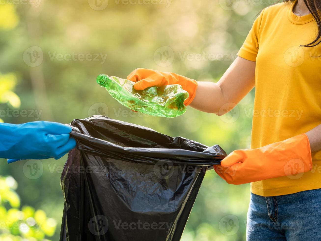 vrijwillige vrouwen verzamelen plastic waterflessen in het park, van mensen die weigeren het afval in de zak te gooien voor recycling foto