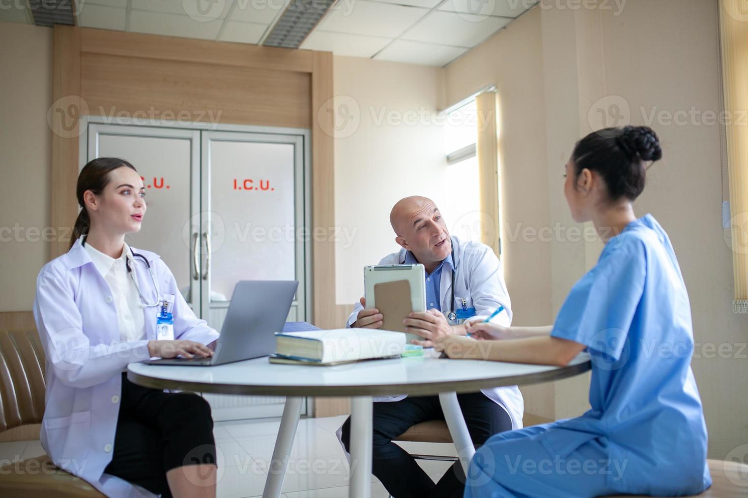 groep artsen die patiëntendossiers raadplegen, oudere arts en collega die de huidige ziektetherapie bespreken op de werkplek. foto
