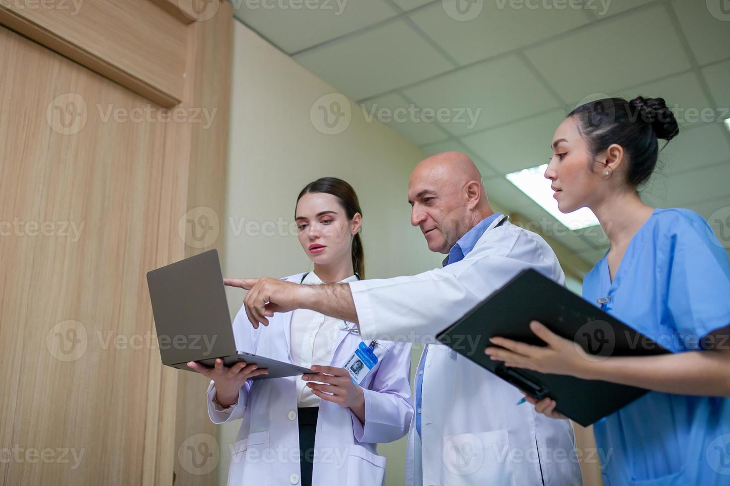 groep artsen die patiëntendossiers raadplegen, oudere arts en collega die de huidige ziektetherapie bespreken op de werkplek. foto