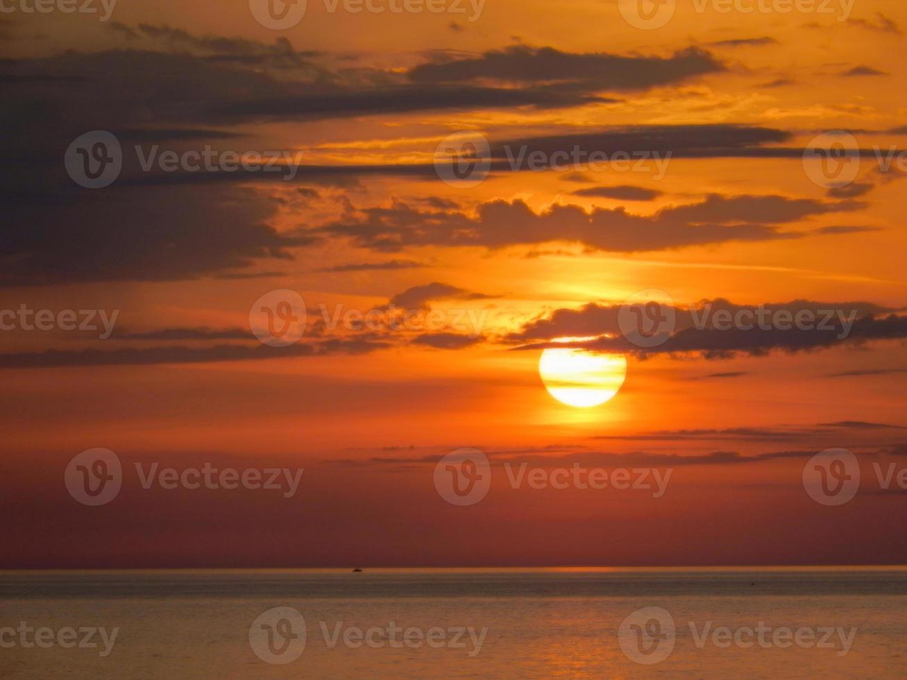 mooie opname van een feloranje zonsonderganghemel boven een zee foto