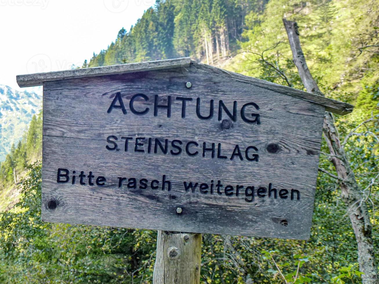 waarschuwingsbord over mogelijke steenslag vragen om snel te gaan in het Duits foto