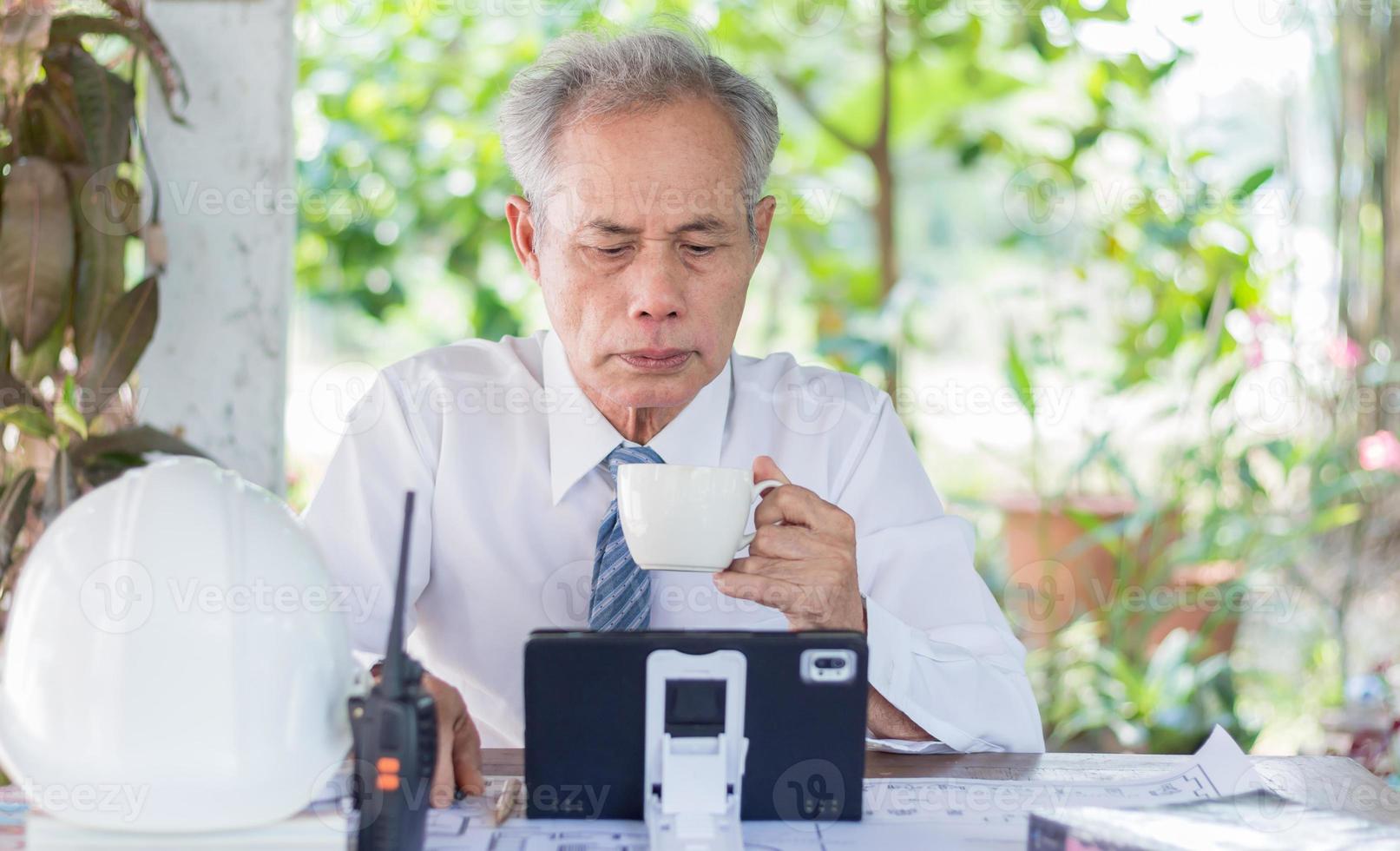 zakenman of ingenieur die tablet-pc leest terwijl hij koffie drinkt, Aziatische ouderlingen foto