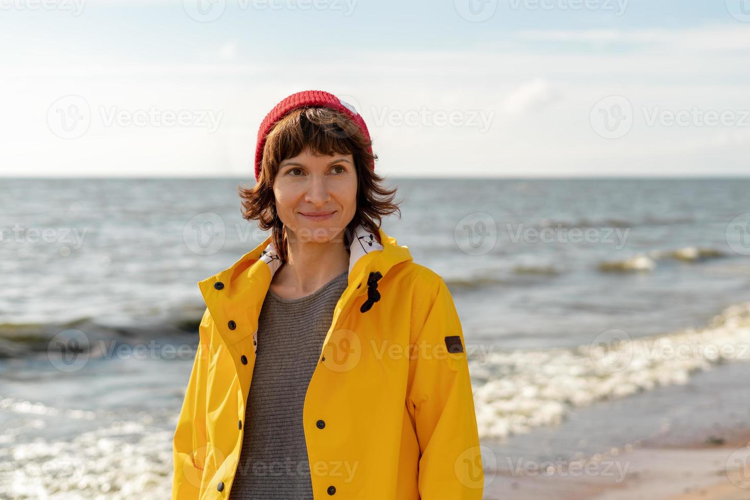 taille portret van volwassen vrouw in felgele mantel en rode hoed op de wal foto