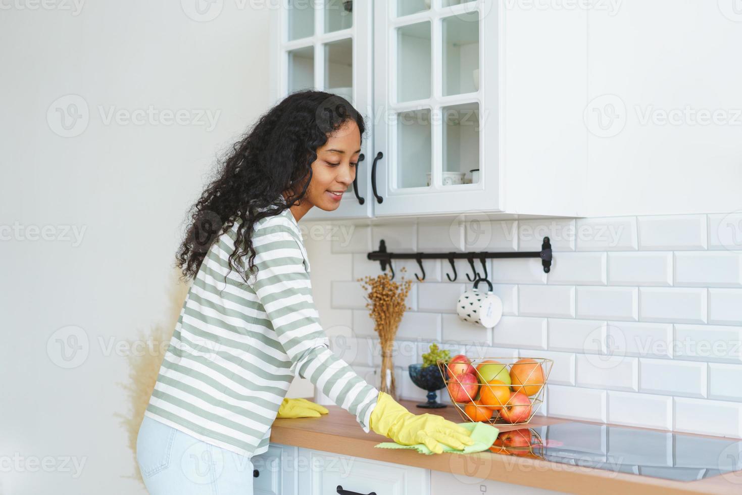 Afro-Amerikaanse vrouw in rubberen handschoenen bezig met huishoudelijke taken in de keuken foto