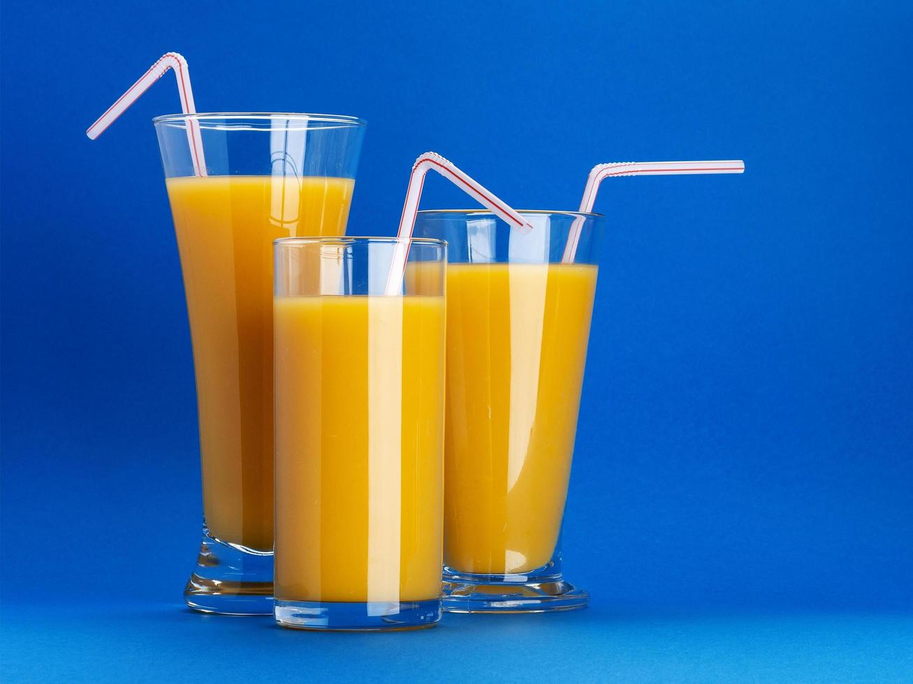 glazen sinaasappelsap op blauwe achtergrond met kopieerruimte foto