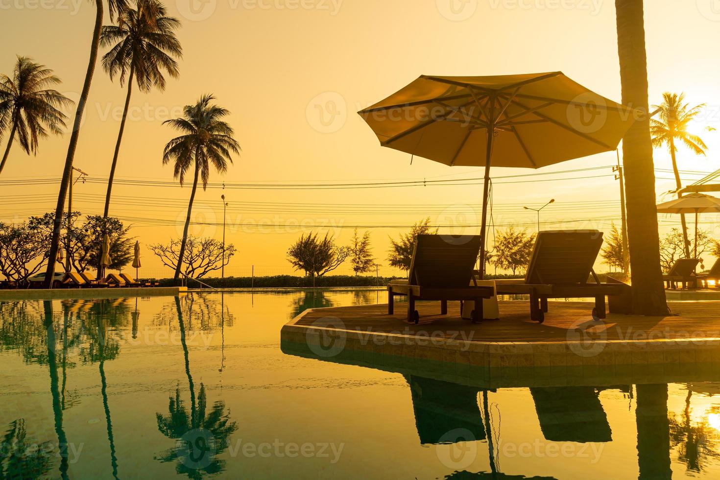 parasol met bed zwembad rond zwembad met oceaan zee achtergrond foto