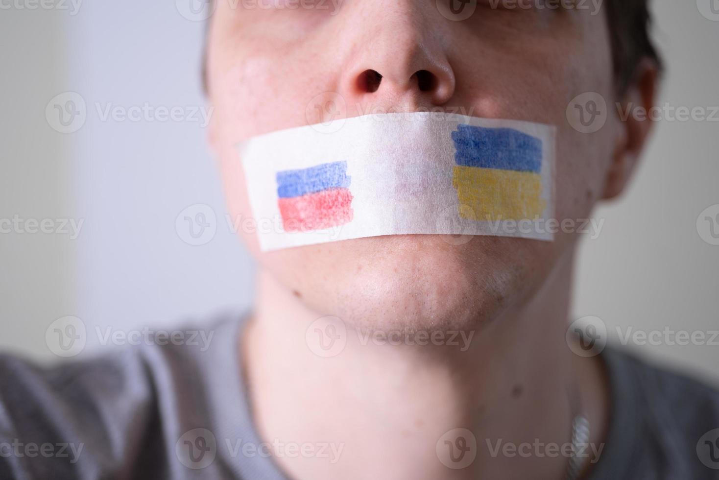 Met plakband afgeplakte mond met de vlag van rusland en oekraïne, proberend te zeggen. foto