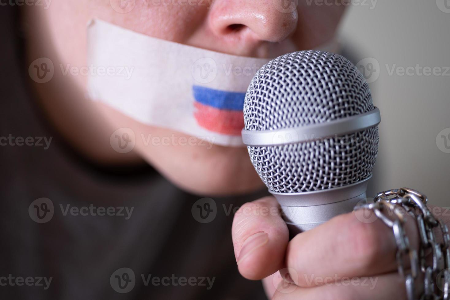 een met ducttape afgeplakte mond met een Russische vlag, die in een microfoon probeerde te spreken. foto
