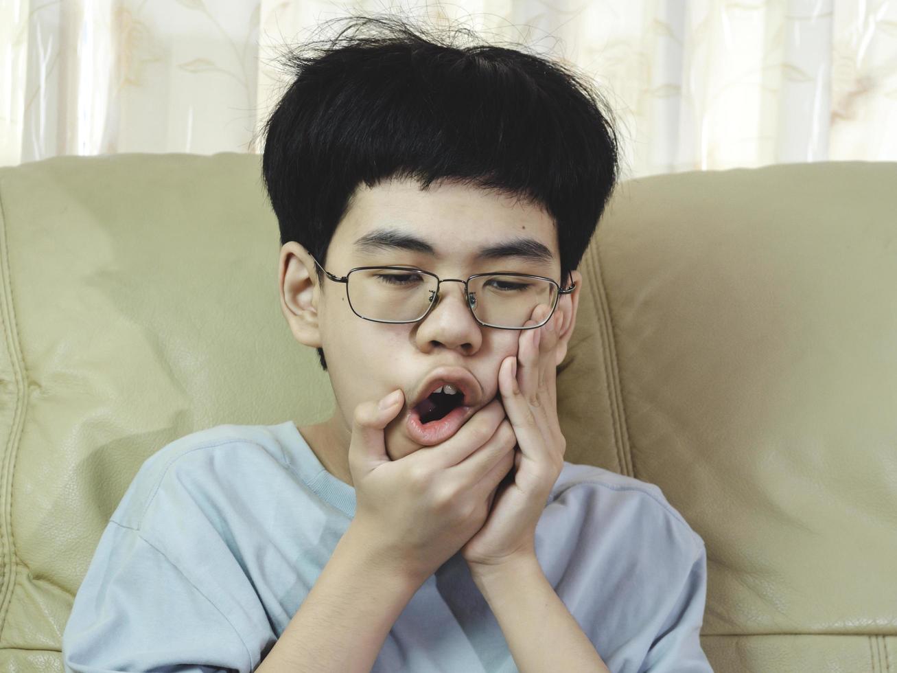 kleine Aziatische jongen lijdt aan kiespijn. hij verdrietig met tandpijn, tandziekte, kind met tandproblemen. afspraak tandarts maken. foto