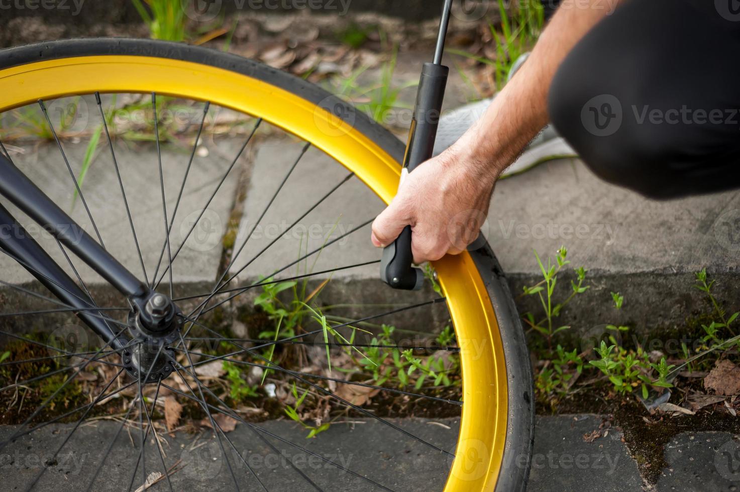 een jonge man pompt het wiel van zijn fiets op. foto
