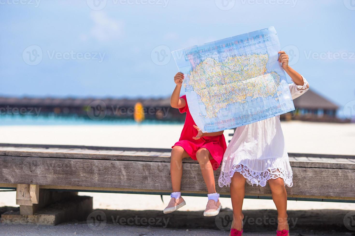 schattige kleine meisjes met kaart van eiland op strand foto