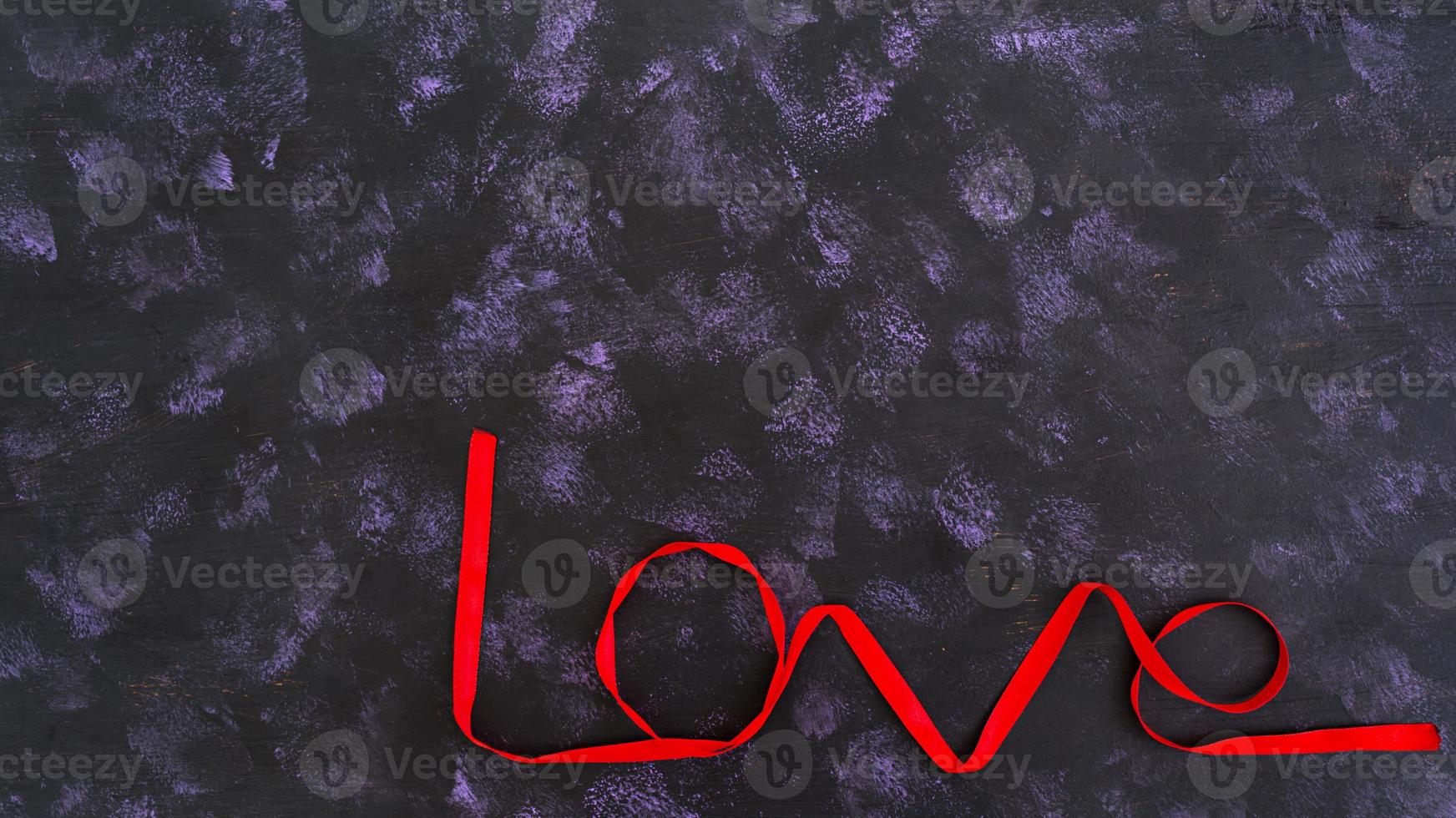 woord liefde gemaakt van rood lint op donkere achtergrond foto