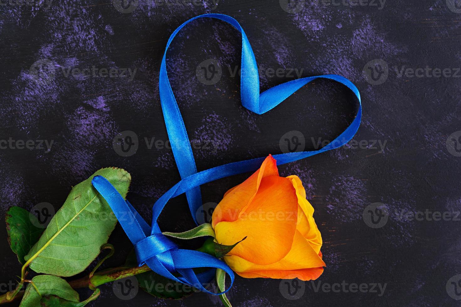 hartvorm gemaakt met lint en rozen op donkere achtergrond. bovenaanzicht foto